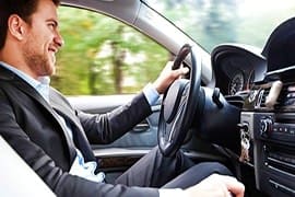 Man in business attire driving a four-wheel drive vehicle through desert landscape in Abu Dhabi